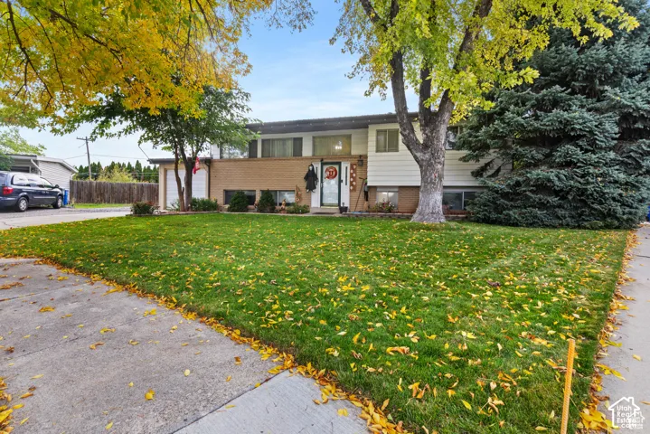 Split-level exterior featuring brick and horizontal siding, an attached garage, and mature trees