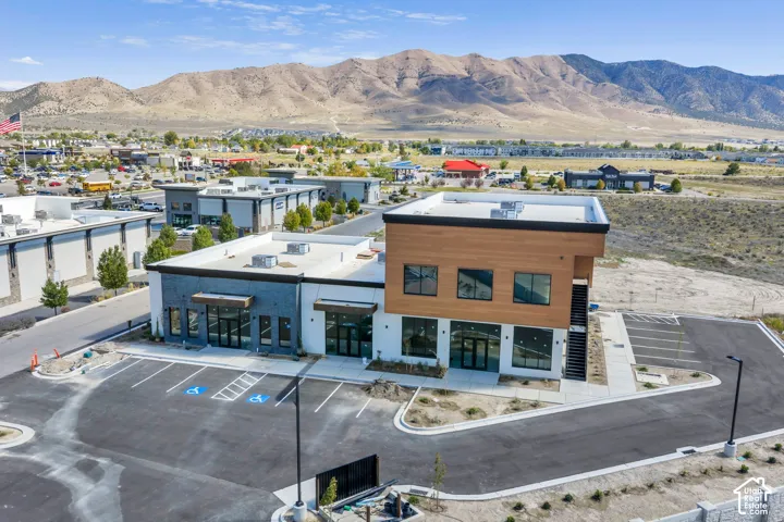 Modern commercial structure featuring dual-tone exterior cladding, horizontal wood-finish siding, asphalt parking area, and mountain backdrop