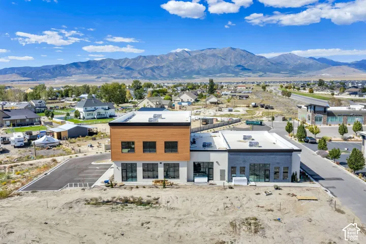Multi-level commercial structure featuring horizontal wood siding, stucco exterior, expansive glass-pane storefront windows, and mountain range backdrop