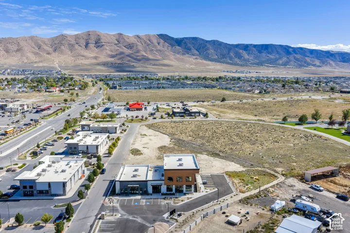 Commercial site featuring paved parking areas, two-story modern building structure, and prominent mountain backdrop
