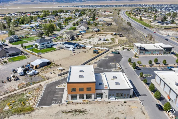 Commercial property featuring a multi-level structure with natural wood-tone cladding, extensive glass storefronts, flat roofing, and a dedicated asphalt parking lot