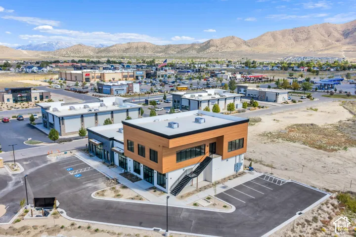 Commercial building featuring a two-story wood-tone facade, flat roof, exterior metal staircase, and dedicated asphalt parking