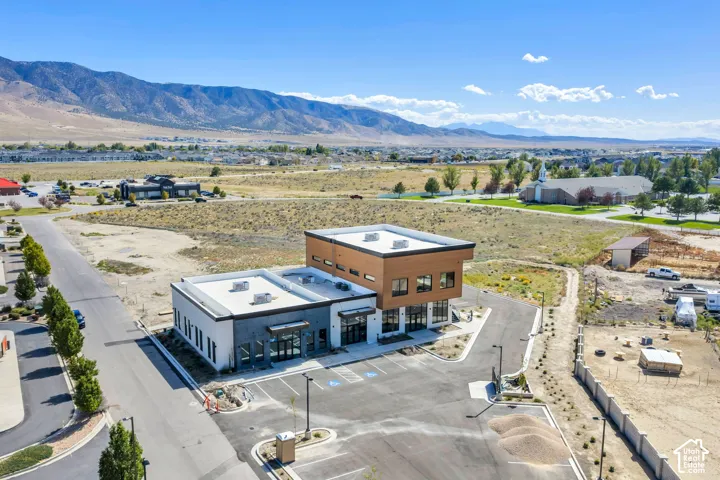 Two-story commercial structure featuring a flat roofline, horizontal wood-finish siding, white masonry exterior, and expansive glass storefront windows, situated on a lot with dedicated asphalt parking