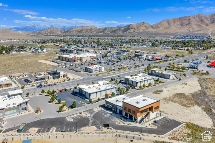 Aerial view of commercial development featuring paved surface parking, multi-tenant building exteriors, exterior staircases, and mountain backdrop