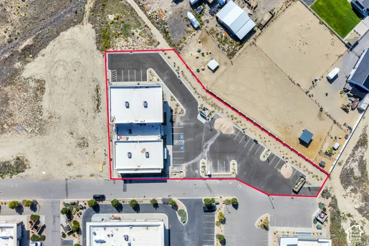 Aerial view featuring a commercial structure with a dedicated asphalt parking lot, marked parking stalls, and perimeter landscaping