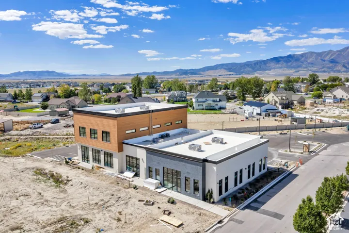 Two-story modern architectural design featuring mixed-material exterior siding, flat roofing with rooftop HVAC units, large-format glass window panels, and mountain backdrops