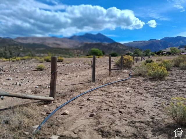 Expansive lot featuring wire fencing, wooden posts, and mountainous scenery