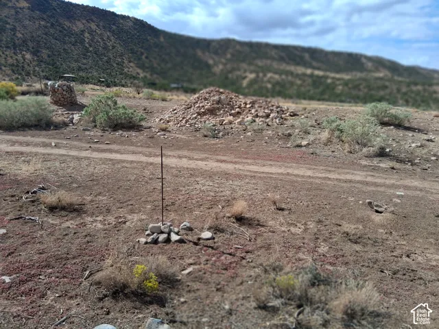 Expansive desert acreage featuring native shrubbery, rock formations, and a backdrop of rugged mountain terrain