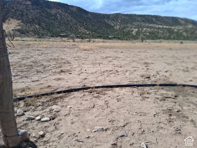 Expansive open acreage featuring wire fencing, irrigation piping, and natural mountainous terrain
