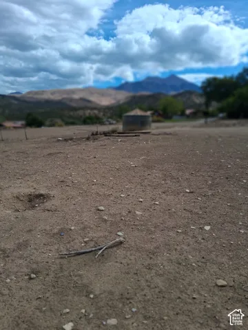 Expansive acreage featuring prominent mountain backdrops and a circular stone-finish reservoir