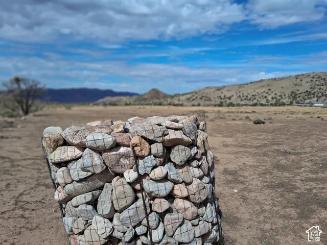 Expansive parcel of land featuring natural terrain and mountain backdrop with a metal wire gabion structure