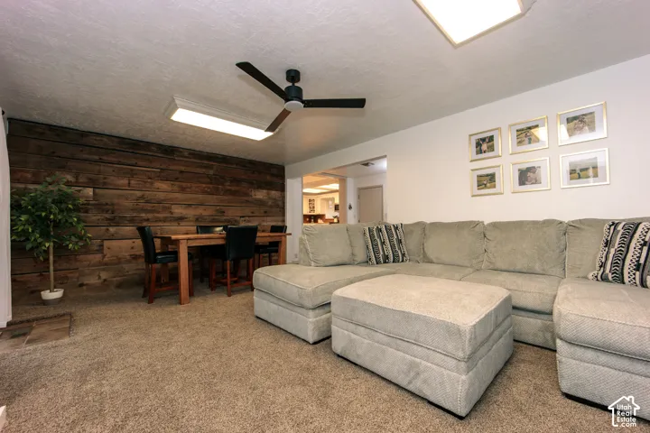 Horizontal wood-plank accent wall, ceiling fan with integrated lighting, and rectangular recessed ceiling fixture
