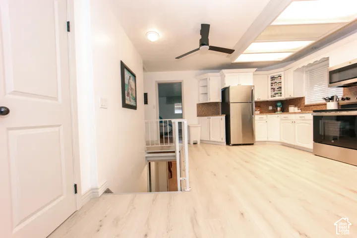 Kitchen featuring white cabinetry, stainless steel appliances, wood-finish flooring, a ceiling fan, and recessed lighting