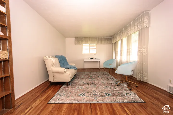 Room featuring wood-finish flooring, built-in wall shelving, and large windows with integrated valances