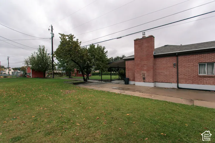 Exterior featuring red brick masonry, a brick chimney, a concrete patio, a covered porch, and a fenced yard