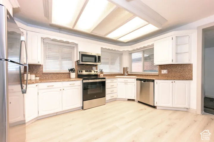 Kitchen featuring white cabinetry, stone-surface countertops, recessed ceiling lighting, wood-finish flooring, and stainless steel appliances