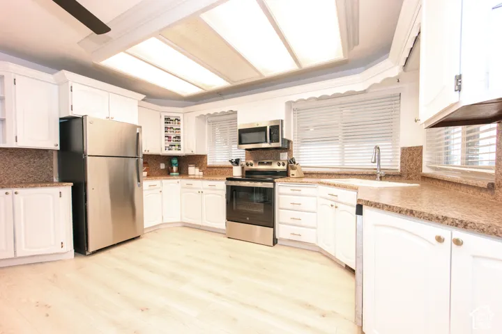 Kitchen featuring white shaker-style cabinetry, stainless steel appliances, speckled stone-finish countertops, wood-finish flooring, and a recessed ceiling light fixture