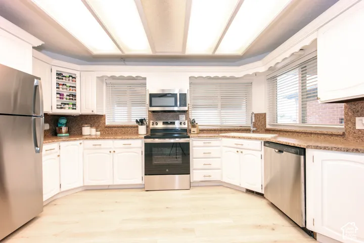 Kitchen featuring white cabinetry, stone-surface countertops, recessed ceiling lighting, and stainless steel appliances including a range, microwave, and dishwasher