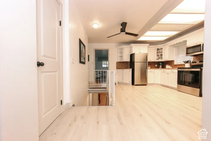 Kitchen featuring white cabinetry, wood-finish flooring, stainless steel appliances, recessed ceiling lighting, and a multi-blade ceiling fan