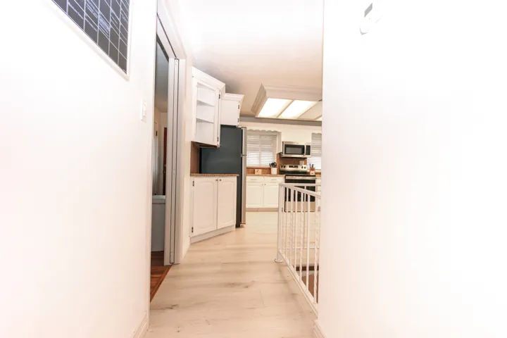 Kitchen featuring white cabinetry, wood-finish flooring, built-in appliances, and recessed tray ceiling lighting
