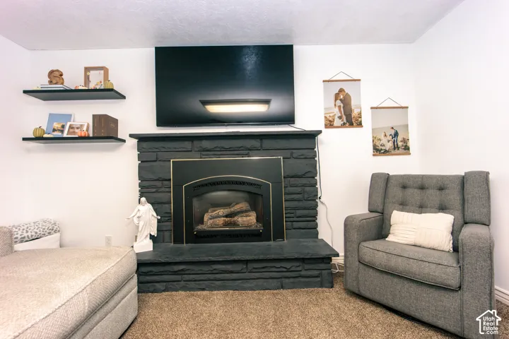 Painted brick fireplace featuring a hearth and a black metal insert, complemented by dual black wall-mounted floating shelves