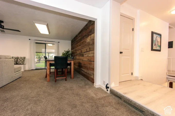 Interior space featuring a reclaimed wood-plank accent wall, carpeting, light-toned wood-finish flooring, and a sliding glass door