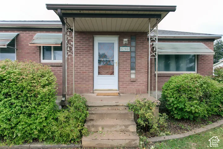 Brick exterior featuring a covered entryway, decorative metal porch supports, glass block accents, and metal window awnings