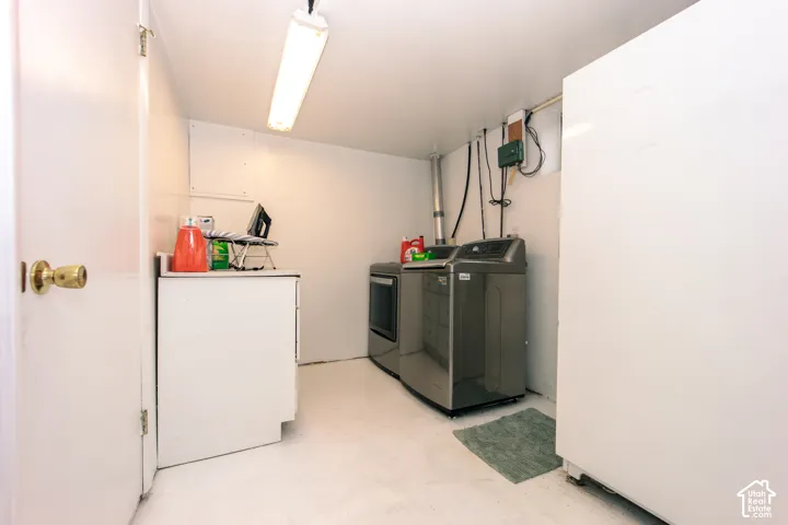 Utility area featuring a built-in white laminate cabinet with a solid surface countertop, overhead fluorescent lighting, and dedicated laundry appliance hookups