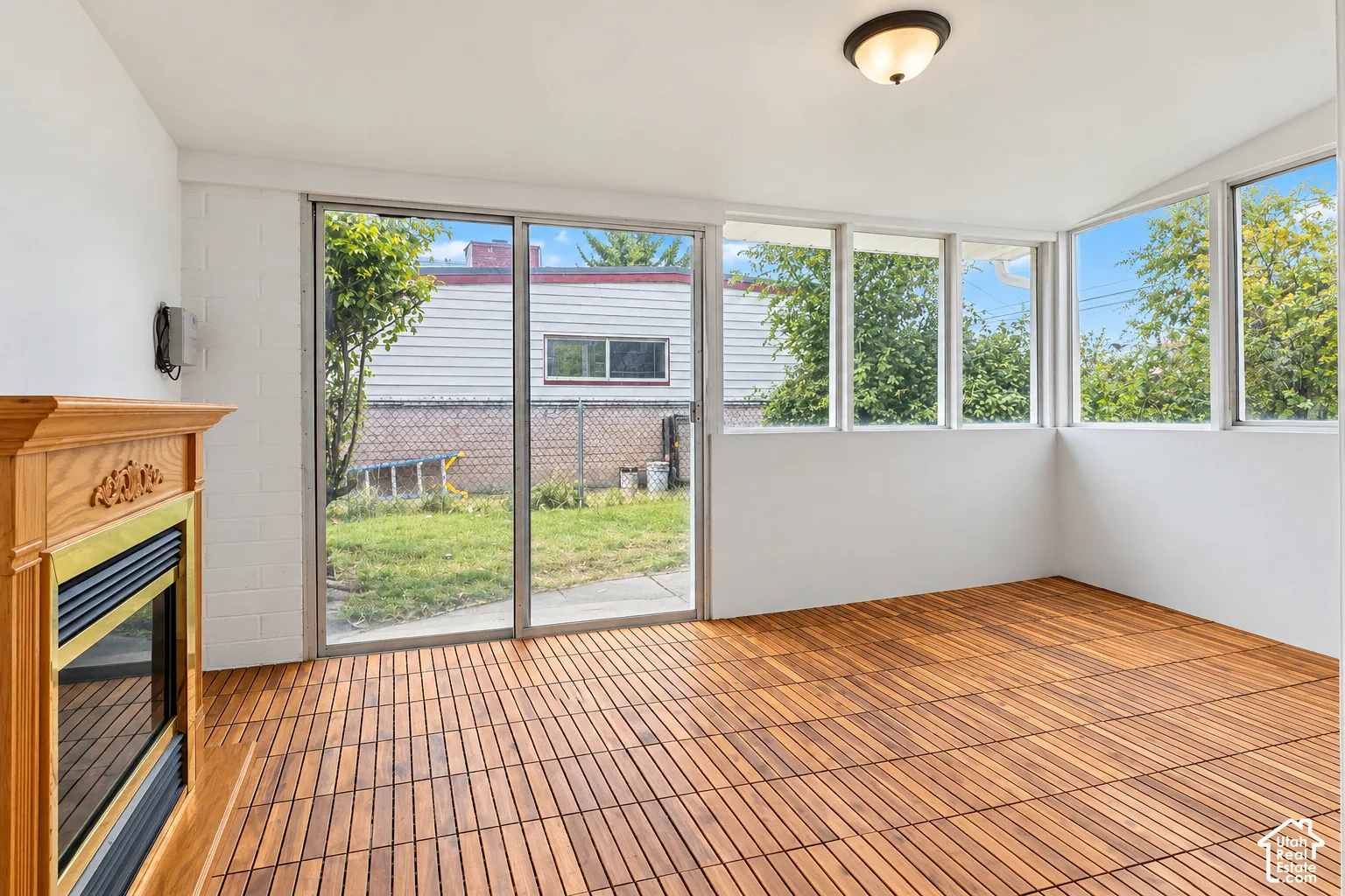 Enclosed sunroom featuring wood-finish slat flooring, a wood-surround fireplace, large windows, and sliding glass doors