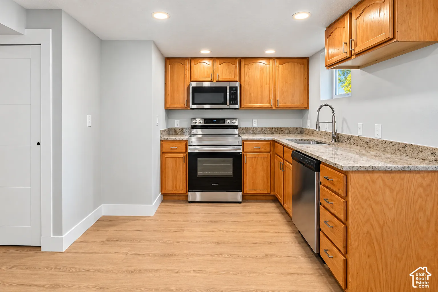 Kitchen featuring shaker-style wood cabinetry, stone countertops, stainless steel appliances, recessed lighting, and wood-finish flooring