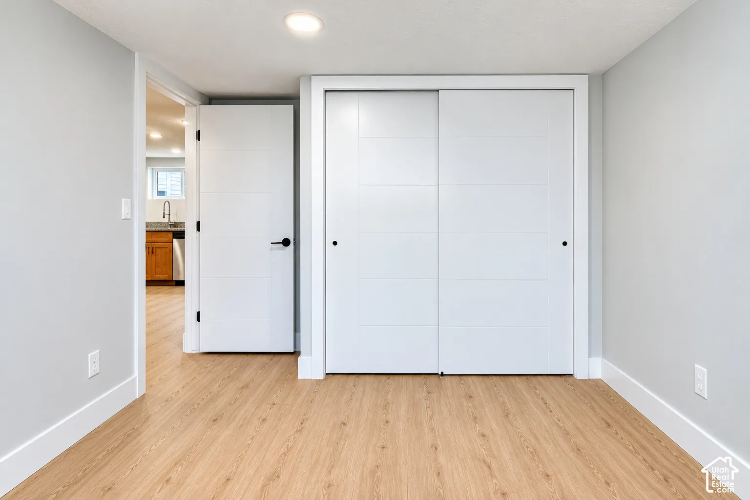 Interior space featuring light-toned wood-finish flooring, sliding closet doors with a multi-panel design, and recessed ceiling lighting