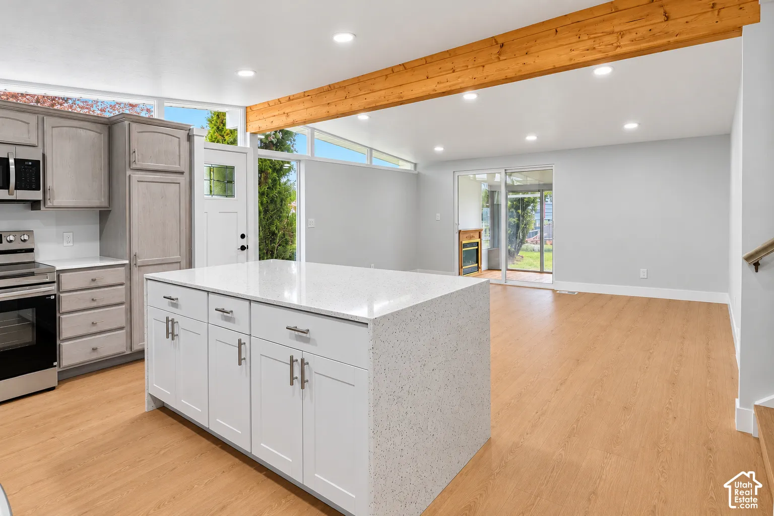 Kitchen featuring a central island with a solid-surface countertop, exposed wood structural beam, clerestory windows, recessed lighting, and wood-finish flooring