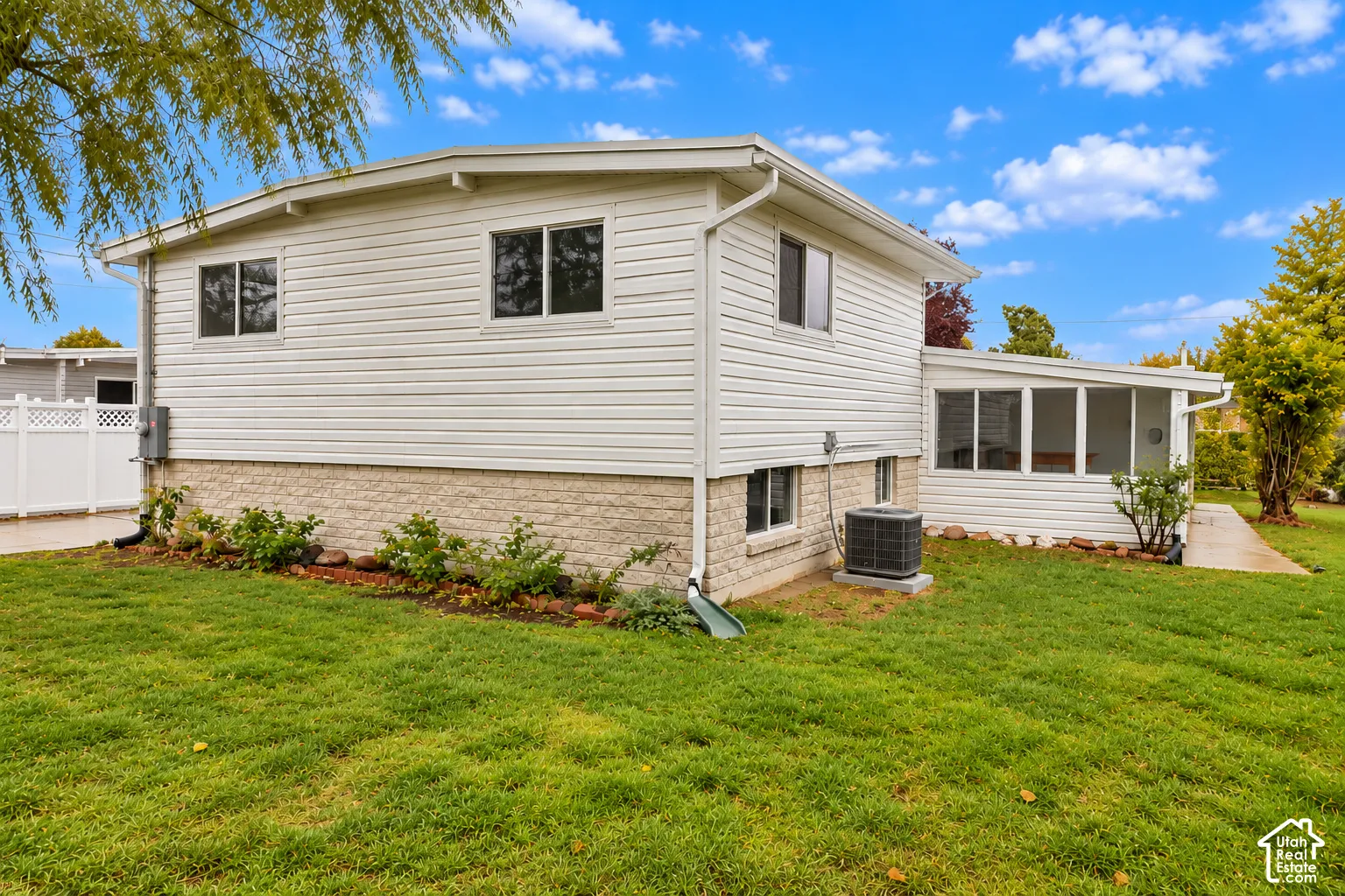 Exterior featuring horizontal siding, stone veneer base, enclosed patio, and vinyl privacy fencing