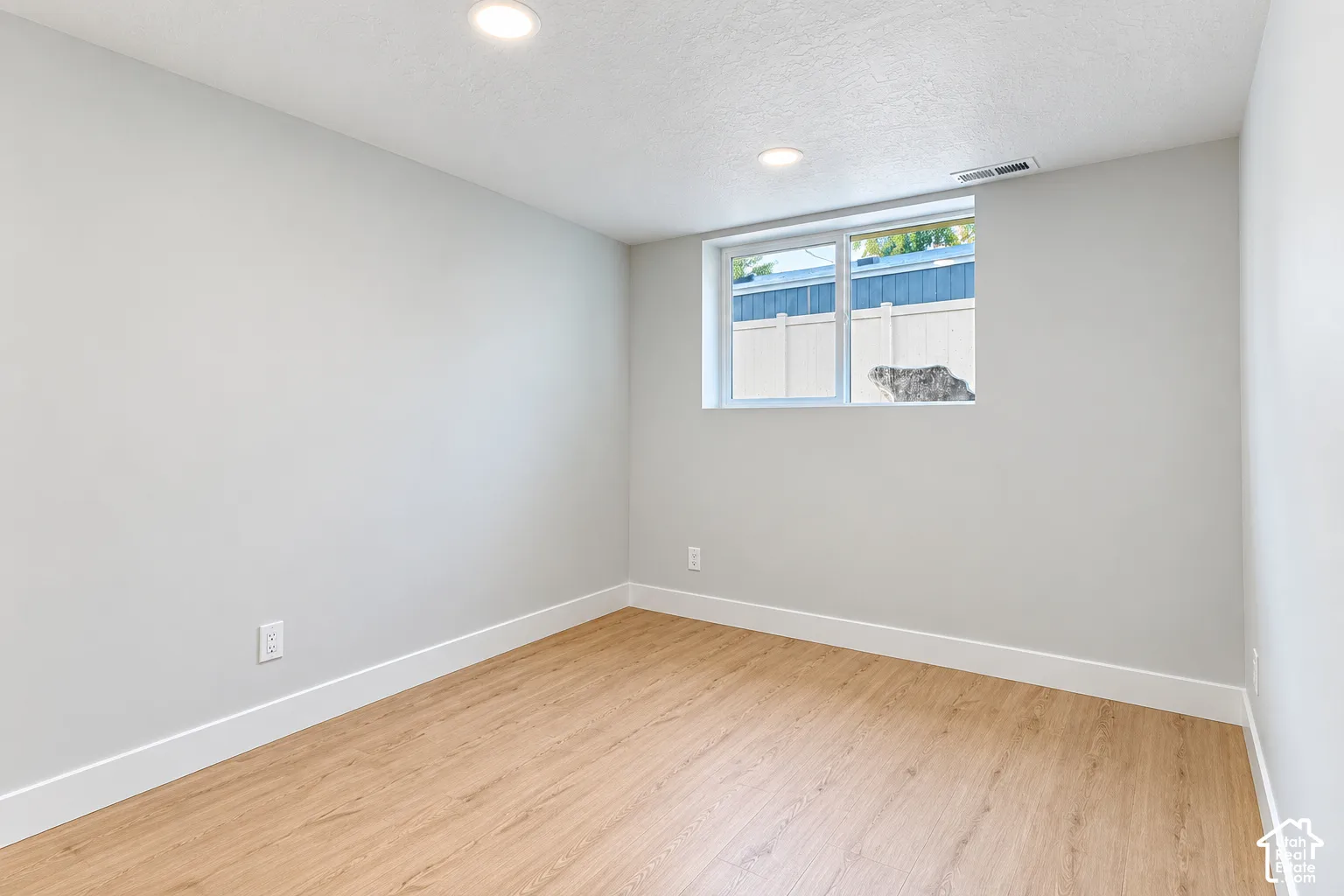Room featuring neutral-toned walls, wood-finish flooring, recessed lighting, and a single-pane horizontal window
