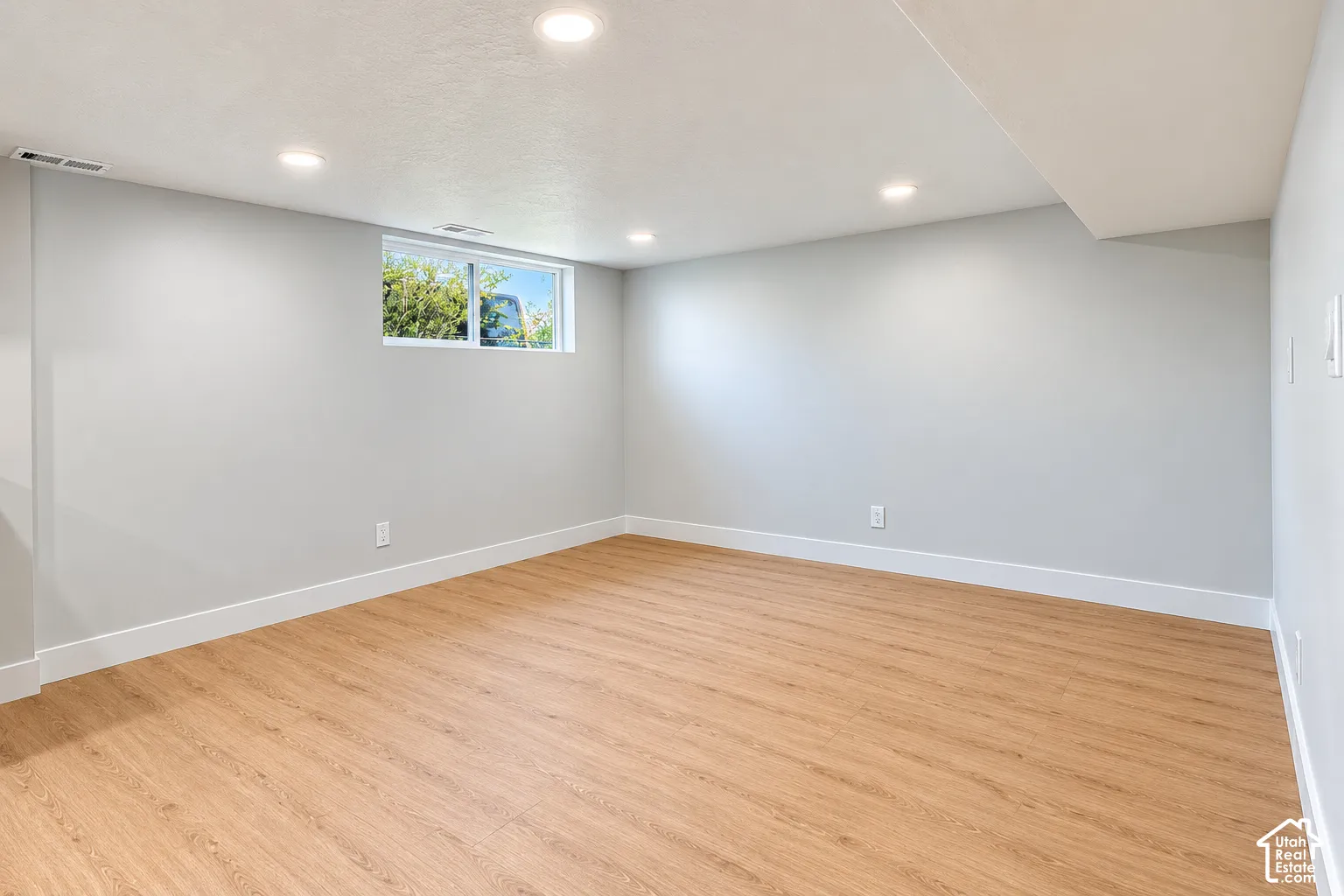 Neutral-toned walls, wood-finish flooring, recessed lighting, and a slider window