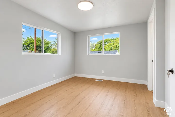 Neutral interior room featuring wood-finish flooring, two sliding windows, and a flush-mount ceiling light fixture