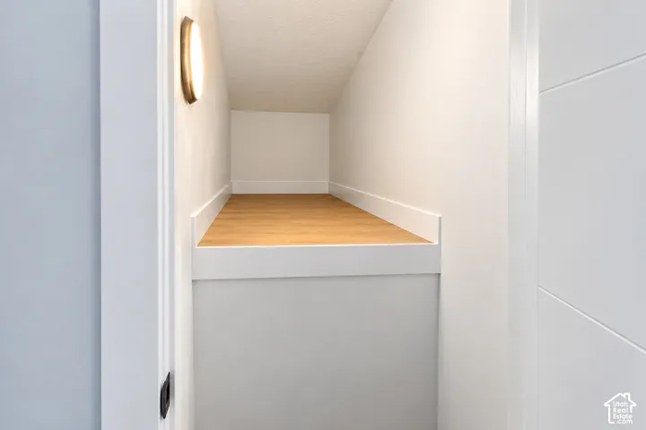 Recessed storage niche featuring wood-finish flooring, crisp white trim, and a wall-mounted circular light fixture