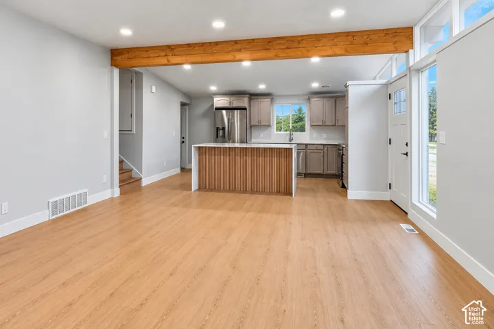 Kitchen featuring wood-finish flooring, a waterfall island, recessed lighting, exposed wood ceiling beam, and clerestory windows