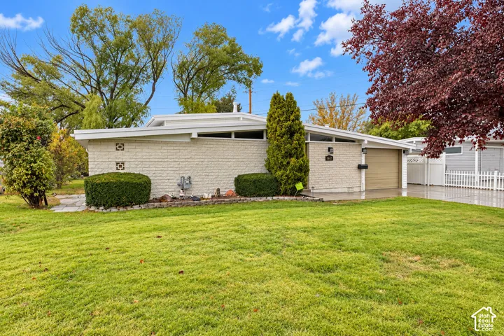 Mid-century modern exterior featuring a low-pitched roofline, clerestory windows, textured stone veneer, and an attached single-car garage