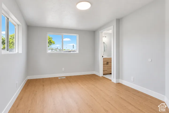 Neutral-toned interior featuring wood-finish flooring, dual sliding windows, and a flush-mount overhead light fixture