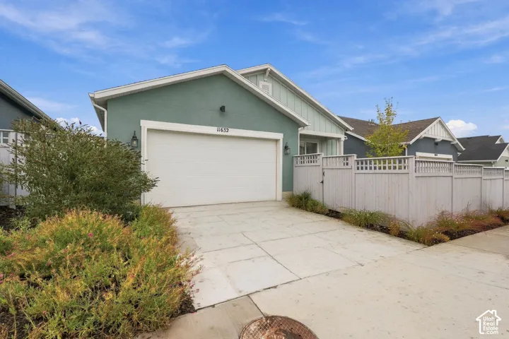 Single-story residence featuring a teal stucco exterior, vertical board-and-batten siding accents, an attached two-car garage, and perimeter privacy fencing
