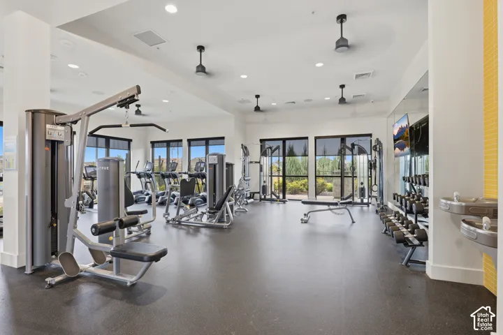 Fitness center featuring recessed lighting, ceiling fans, oversized windows, full-length mirrors, and wall-mounted water fountains