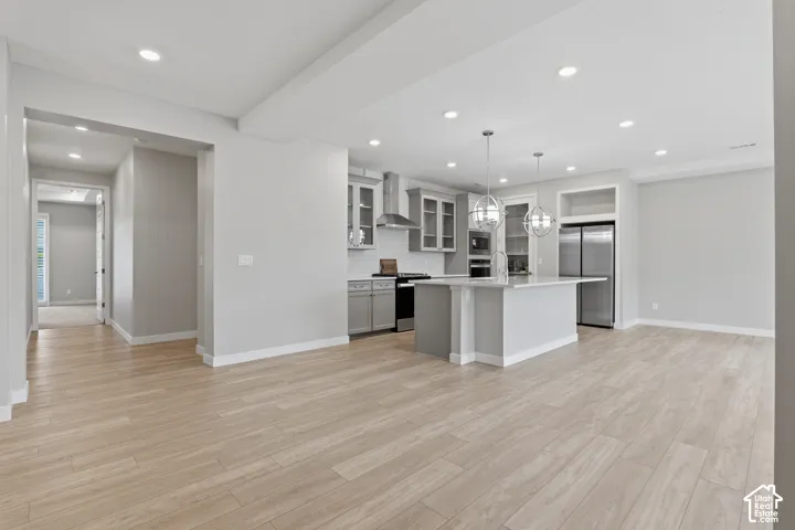 Kitchen featuring wood-finish flooring, a central island with quartz countertop, recessed lighting, stainless steel appliances, and shaker-style cabinetry with glass-front uppers