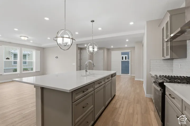 Kitchen featuring a central island with a quartz countertop, wood-finish cabinetry, wood-finish flooring, recessed lighting, and spherical pendant fixtures
