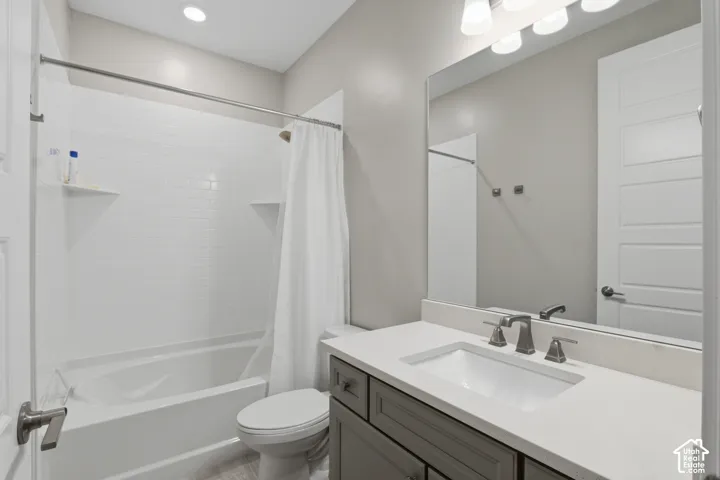 Bathroom featuring a vanity with a light-toned countertop, undermount sink, grey shaker-style cabinetry, and a full-width mirror