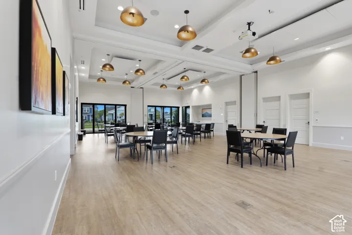 Spacious interior featuring wood-finish flooring, recessed coffered ceilings, multi-pendant dome lighting, and large glass-panel sliding doors