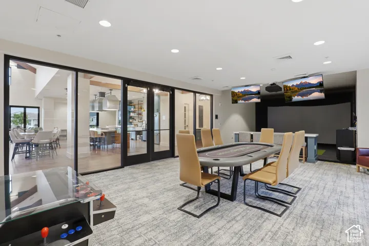 Open-concept recreational space featuring floor-to-ceiling glass panel walls with black frames, recessed lighting, and a built-in golf simulator enclosure
