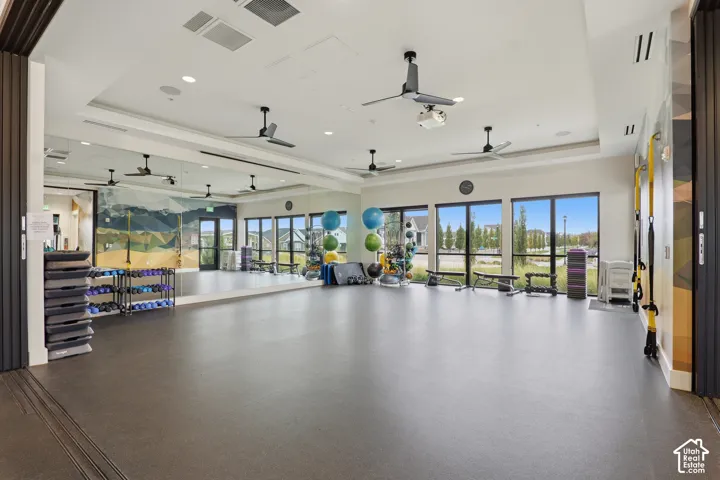 Fitness studio featuring resilient rubber flooring, wall-to-wall mirrors, recessed lighting, ceiling fans, and floor-to-ceiling windows
