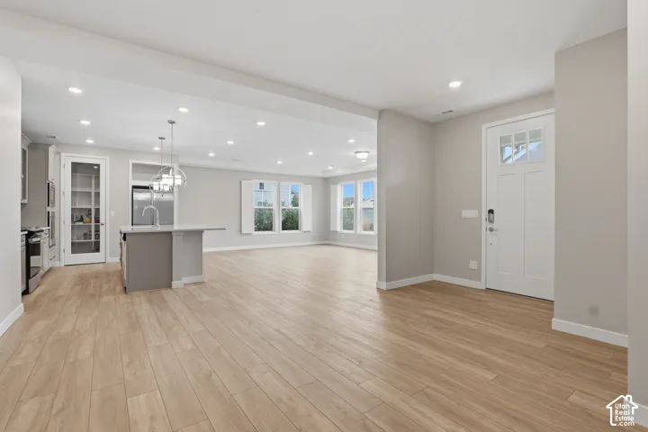 Open-concept interior featuring wood-finish flooring, recessed lighting, a center kitchen island, and a walk-in pantry with a glass-panel door