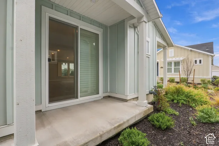 Covered concrete patio with board-and-batten siding, glass sliding door, and square support columns